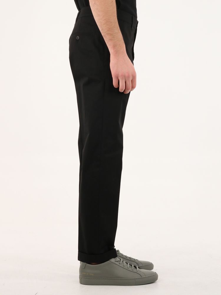 Golden collection black chinos with straight leg and two front pockets. It features a detachable white patch with embroidered red letter G and two double gold stars on the back. The model is 184cm tall and wears size 48.