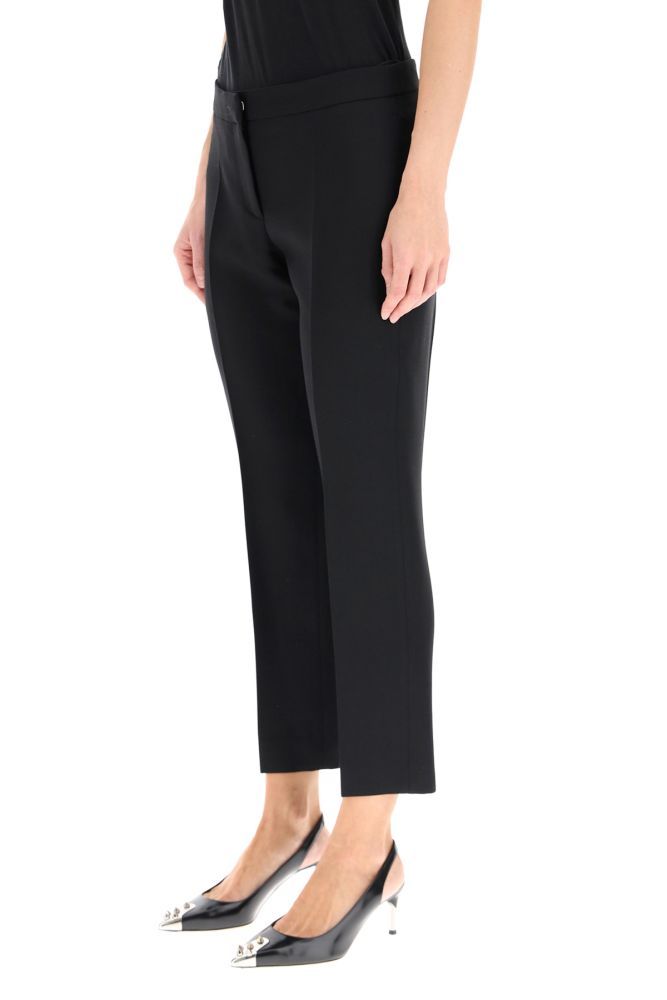Tailored cigarette trousers by Alexander McQueen in light wool and silk fabric with central pleat and ankle length. The straight and tapered leg line is characterized by side slit pockets, a welt pocket on the back and a front closure with zip and concealed hook. The model is 177 cm tall and wears size IT 40.