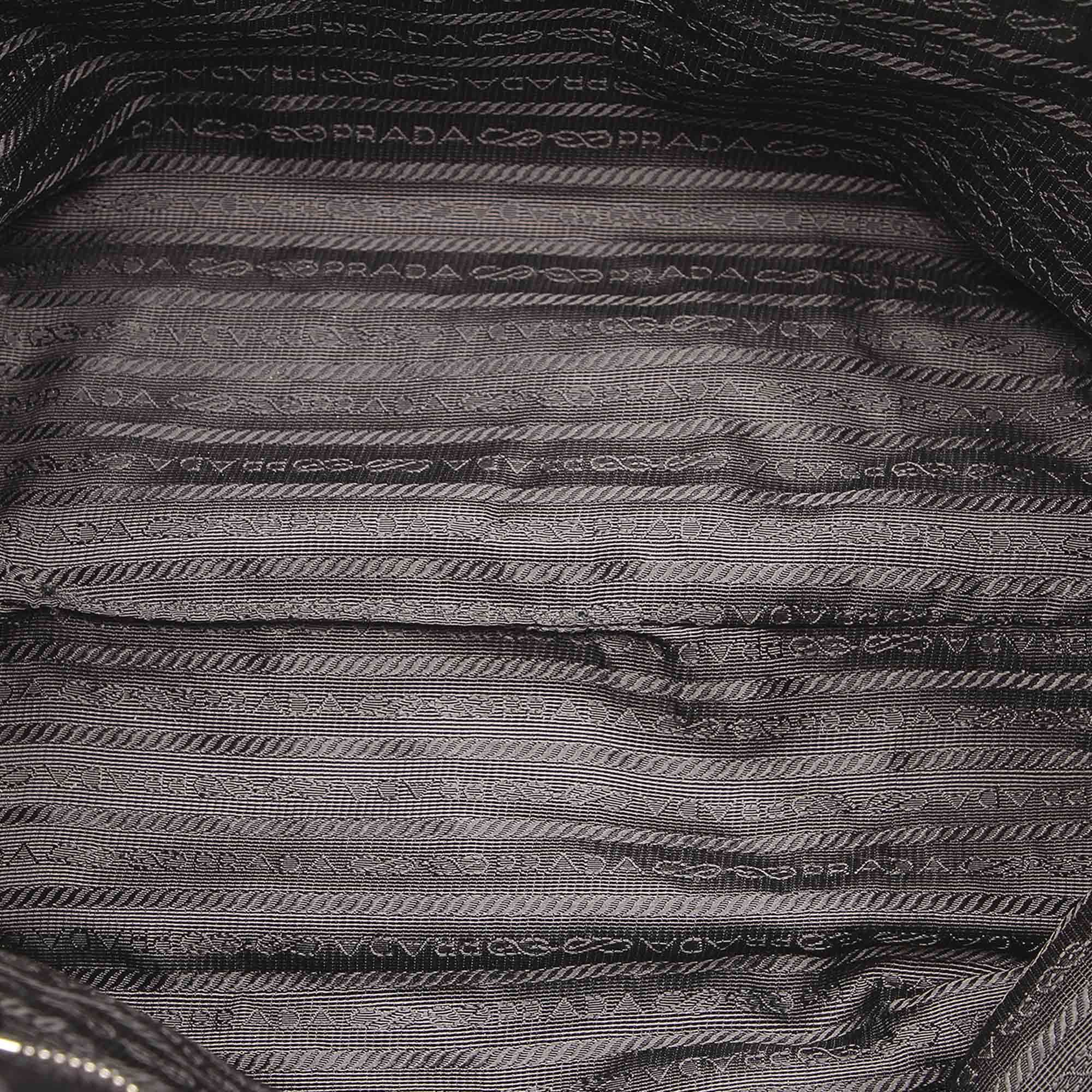 VINTAGE. RRP AS NEW. This handbag features a nylon body with a ribbon detail, rolled leather handles, an open top with a magnetic closure, and an interior zip pockets.Exterior back is discolored and out of shape. Exterior bottom is discolored and out of shape. Exterior corners is discolored and out of shape. Exterior front is discolored and out of shape. Exterior handle is discolored. Exterior side is discolored and out of shape. Studs is tarnished.

Dimensions:
Length 23cm
Width 40cm
Depth 15cm
Hand Drop 10cm
Shoulder Drop 10cm

Original Accessories: Authenticity Card

Serial Number: BN1601
Color: Black
Material: Fabric x Nylon x Leather x Calf
Country of Origin: Italy
Boutique Reference: SSU90102K1342


Product Rating: GoodCondition