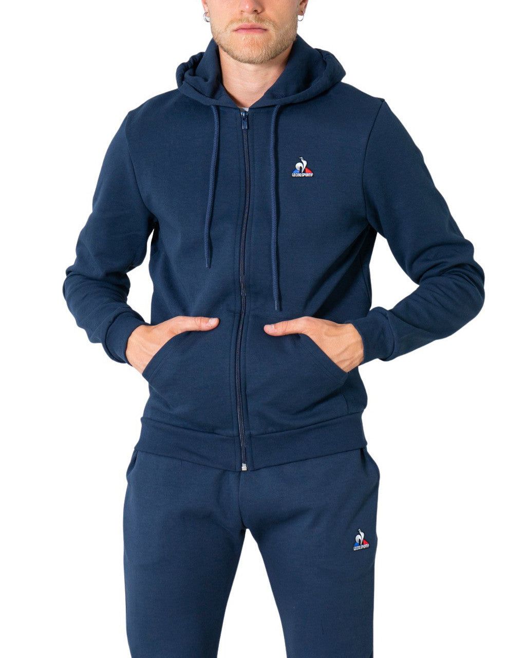 Brand: Le Coq Sportif
Gender: Men
Type: Sweatshirts
Season: Fall/Winter

PRODUCT DETAIL
• Color: blue
• Fastening: with zip
• Sleeves: long
• Collar: hood
• Pockets: front pockets

COMPOSITION AND MATERIAL
• Composition: -85% cotton -15% polyester 
•  Washing: machine wash at 30°
