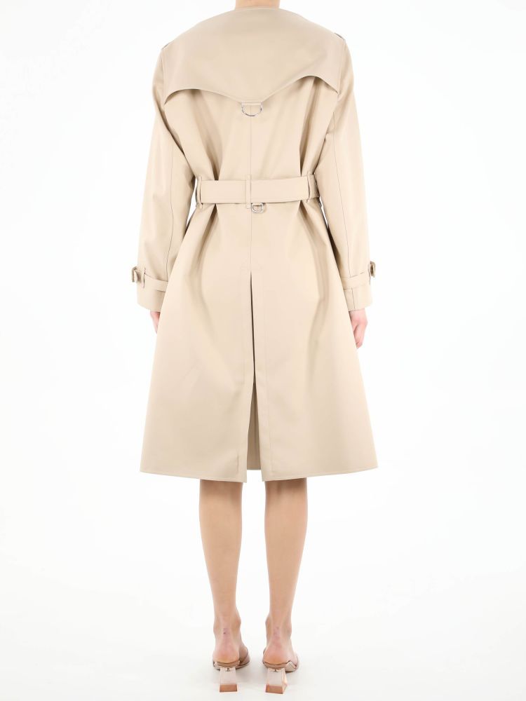 Beige cotton raincoat with double-breasted closure. It features front buttons, adjustable belt on waist, two side buttoned welt pockets, adjustable buckle on cuffs and back slit. The model is 178cm tall and wears size 8.