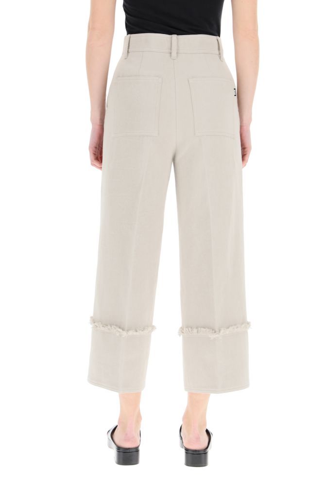 High-waisted culotte trousers in lightweight cotton and linen denim by MSGM. They feature maxi sewn cuffs with fringed trim, zip fly and button closure, side slash pockets, rear patch pockets. Logo label at back. The model is 177 cm tall and wears a size IT 38.