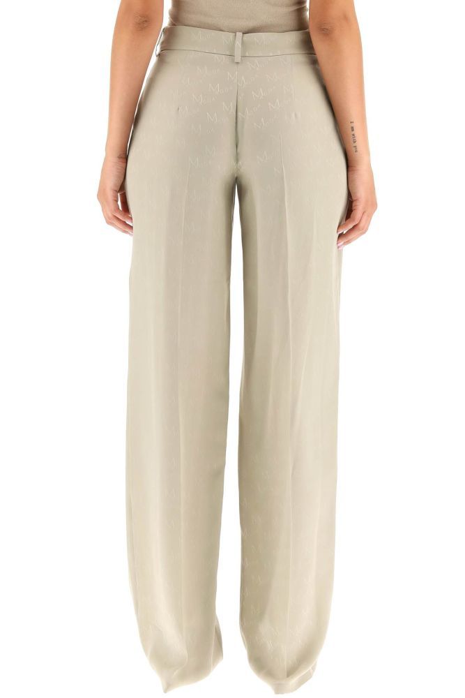 Wide-leg trousers in pure silk crepe envers with all-over jacquard logo by Magda Butrym. They feature a regular waist cut with double front pleat, ironed crease, concealed zip and hook closure, belt loops, side slash pockets. The model is 177 cm tall and wears a size FR 34.