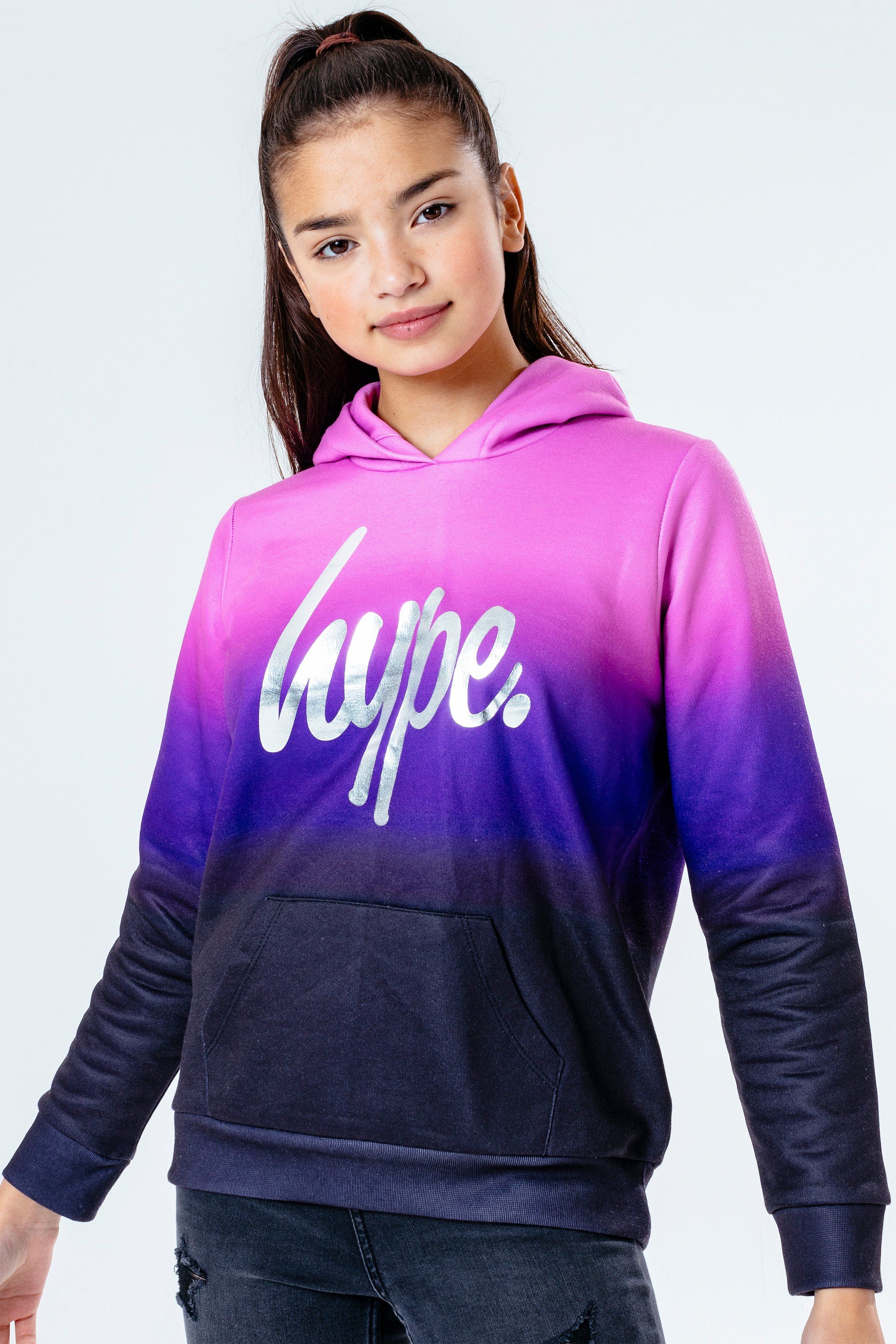Update your 'drobe with the HYPE. Sweetshop Fade Kids Pullover Hoodie. Designed in a black and light purple, purple and black colour palette in a 60% polyester and 40% cotton fabric base for supreme comfort in our standard unisex kids jumper shape. With a fixed hood, kangaroo pocket, long sleeves and fitted hem and cuffs. Finished with the iconic HYPE. script logo in a silver foil transfer. Wear with cycle shorts for an on-trend look. Machine wash at 30 degrees.