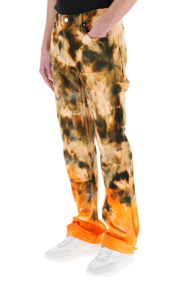 Amiri workwear-inspired trousers in cotton denim with an all-over tie-dye motif. Relaxed straight fit, regular waist with belt loops and several multifunctional pockets. Button fly, hammer loop. Double knee panel, side openings at the lower leg with concealed snap buttons. Leather jacron with metal logo on the back waistband. Metal logo tag on the back pocket. The model is 187 cm tall and wears a size 30.