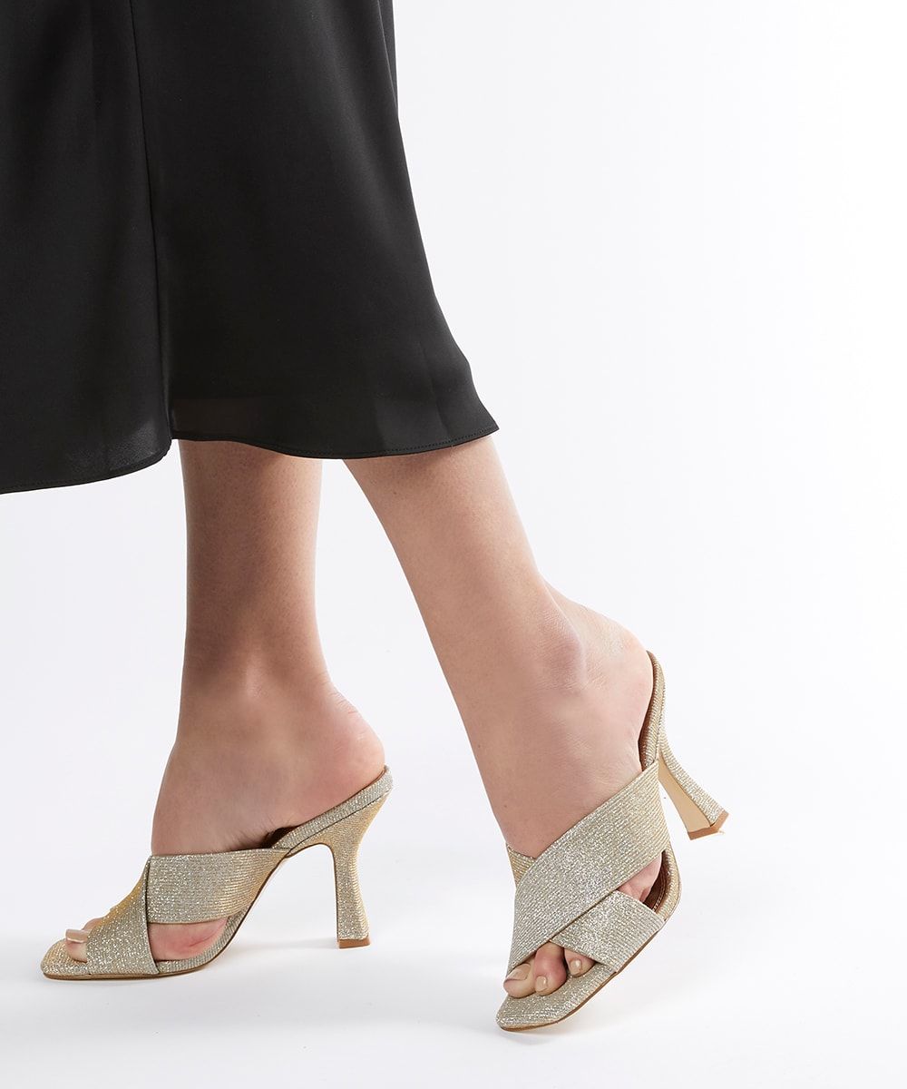 Chic and understated, these modern mules feature wide cross straps and a tonal colour palette. A flared high heel completes the look.