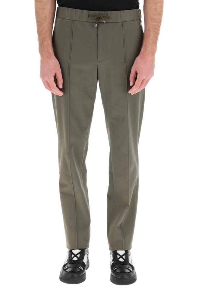 Jogging-style trousers by VALENTINO, made from pure cotton gabardine with elasticated waistband and drawstring. The slightly relaxed fit garment features side slant pockets and rear welt pockets with button. The model is 183 cm tall and wears a size IT 46.