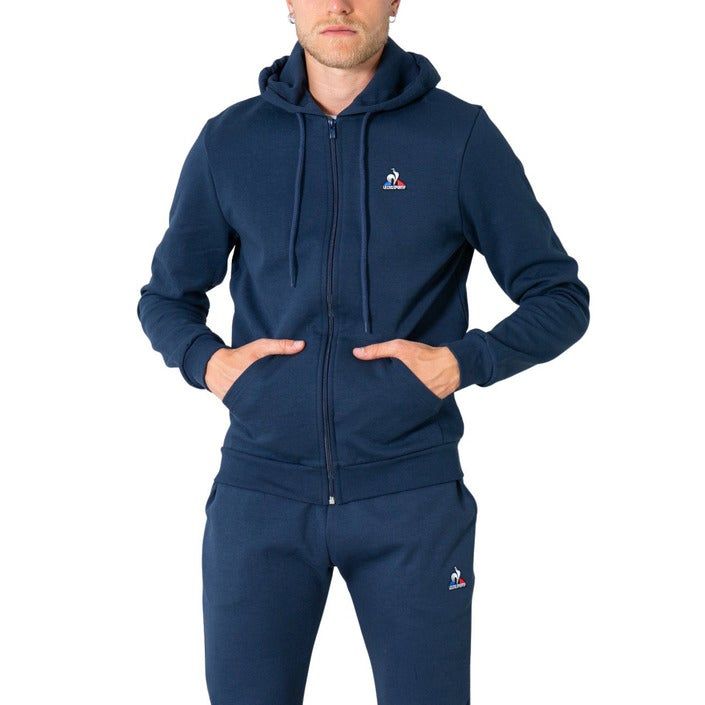 Brand: Le Coq Sportif
Gender: Men
Type: Sweatshirts
Season: Fall/Winter

PRODUCT DETAIL
• Color: blue
• Fastening: with zip
• Sleeves: long
• Collar: hood
• Pockets: front pockets

COMPOSITION AND MATERIAL
• Composition: -85% cotton -15% polyester 
•  Washing: machine wash at 30°