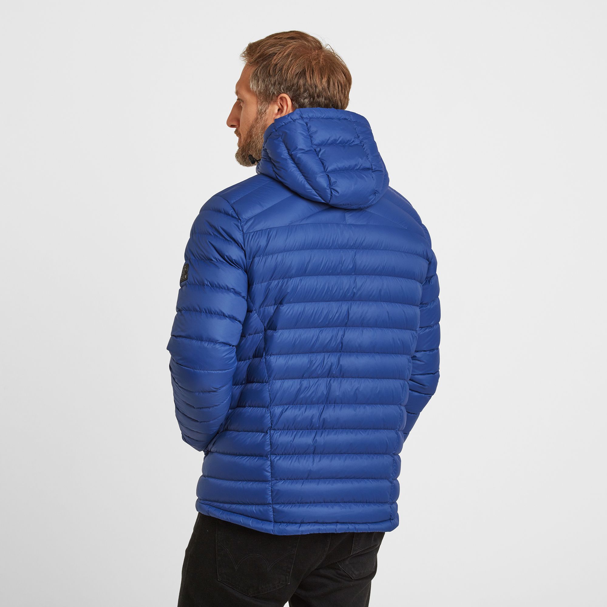 Perfect for adding a layer of warmth without any bulk, our Drax down filled mens jacket with adjustable hood feels silky-soft, incredibly light and packs down small into a zip up inside pocket. You'll have no trouble finding room for it in your case when you go away, and it also makes a handy travel pillow. This padded jacket gets its incredible warmth from naturally insulating duck down that traps heat without being bulky. Quilted bands, a panelled cut and a hood that hugs your neck mean it feels as good as it looks, and it has thoughtful details like a soft chin cover over the top of the zip. Designed to squish down really small, then spring back into shape, Drax has roomy side pockets protected by an elasticated flap, light elastic at the cuffs and small toggle adjusters at the hem keep the chill out.  Designed in Yorkshire, where we always need layers, our Drax mens hooded jacket is ideal for wearing over a top when it's only a bit chilly or layering under a coat when the wind is howling. Reflecting our Spen Valley ethos of Truth Over Glory, it has a TOG24 logo proudly printed on the chest.