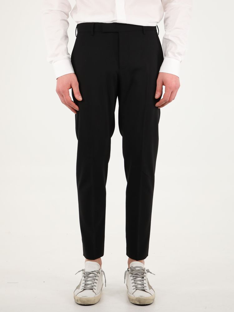 Black wool trousers with straight fit. They feature two side welt pockets, two rear pockets with button, rear charm and belt loops. The model is 184cm tall and wears size 50.  