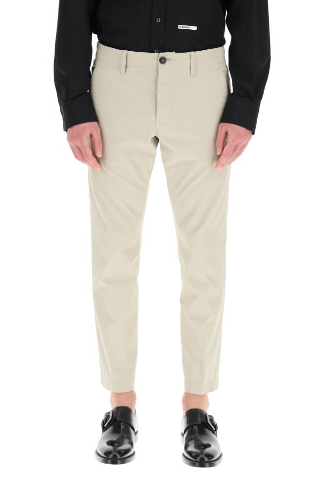Dsquared2 low-waisted chino trousers in cotton twill with ankle length, featuring button closure, side slash pockets, rear jetted pockets with button, belt loops. Detailed with signature maple leaf printed on the back. The model is 187 cm tall and wears a size IT 46.