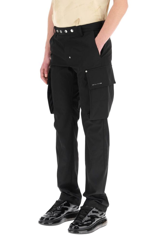 1017 ALYX 9SM nylon trousers with side cargo pockets and metal rivets. Closure with zip and metal press buttons, side slanted pockets, rear welt pockets. Metal logo detail on the front pocket. Regular fit. The model is 187 cm tall and wears a size IT 48.
