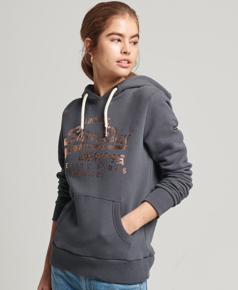 Our Vintage logo is part of our heritage and it's become iconic. Become part of that history with the Vintage Logo Tonal hoodie. The classic hoodie design that lives in so many wardrobes is paired with a crushed effect foil print logo that elevates this staple.Relaxed fit – the classic Superdry fit. Not too slim, not too loose, just right. Go for your normal sizeDrawcord hoodFront pouch pocketRibbed cuffs and hemSleeve logo patchFoil printed logoBrushed lining