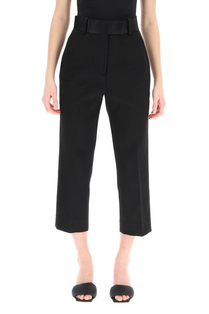 Khaite trousers in stretch cotton blend micro-piquet, finished with silk satin waistband and rear pocket piping. High-rise straight-leg cut with a slim fit and a cropped length, concealed zip and hook closure, side French pockets. The model is 177 cm tall and wears a size US 4.