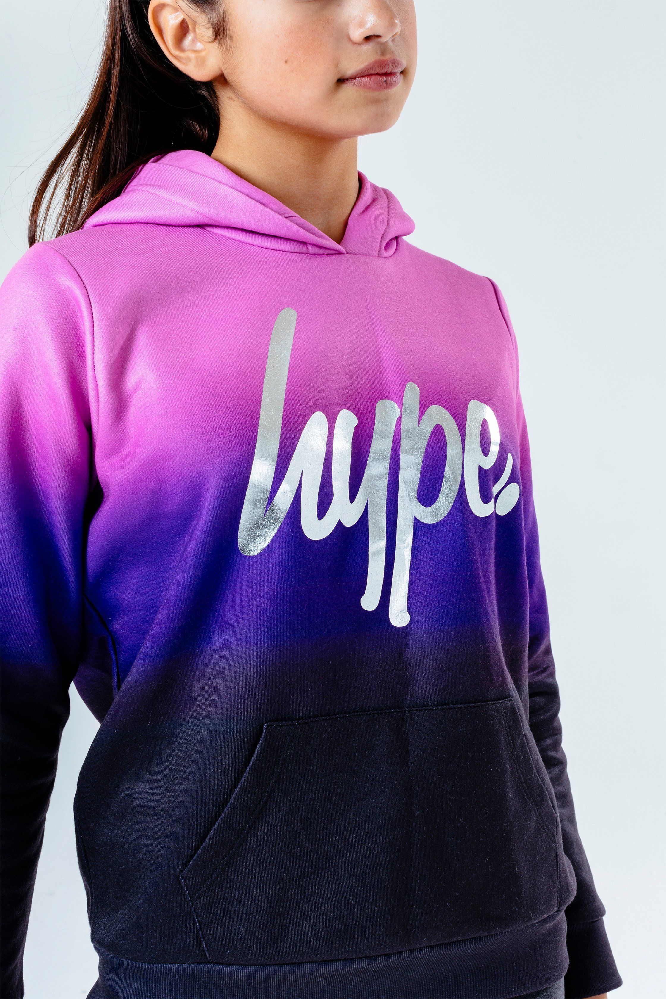Update your 'drobe with the HYPE. Sweetshop Fade Kids Pullover Hoodie. Designed in a black and light purple, purple and black colour palette in a 60% polyester and 40% cotton fabric base for supreme comfort in our standard unisex kids jumper shape. With a fixed hood, kangaroo pocket, long sleeves and fitted hem and cuffs. Finished with the iconic HYPE. script logo in a silver foil transfer. Wear with cycle shorts for an on-trend look. Machine wash at 30 degrees.