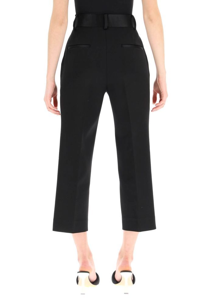 Khaite trousers in stretch cotton blend micro-piquet, finished with silk satin waistband and rear pocket piping. High-rise straight-leg cut with a slim fit and a cropped length, concealed zip and hook closure, side French pockets. The model is 177 cm tall and wears a size US 4.