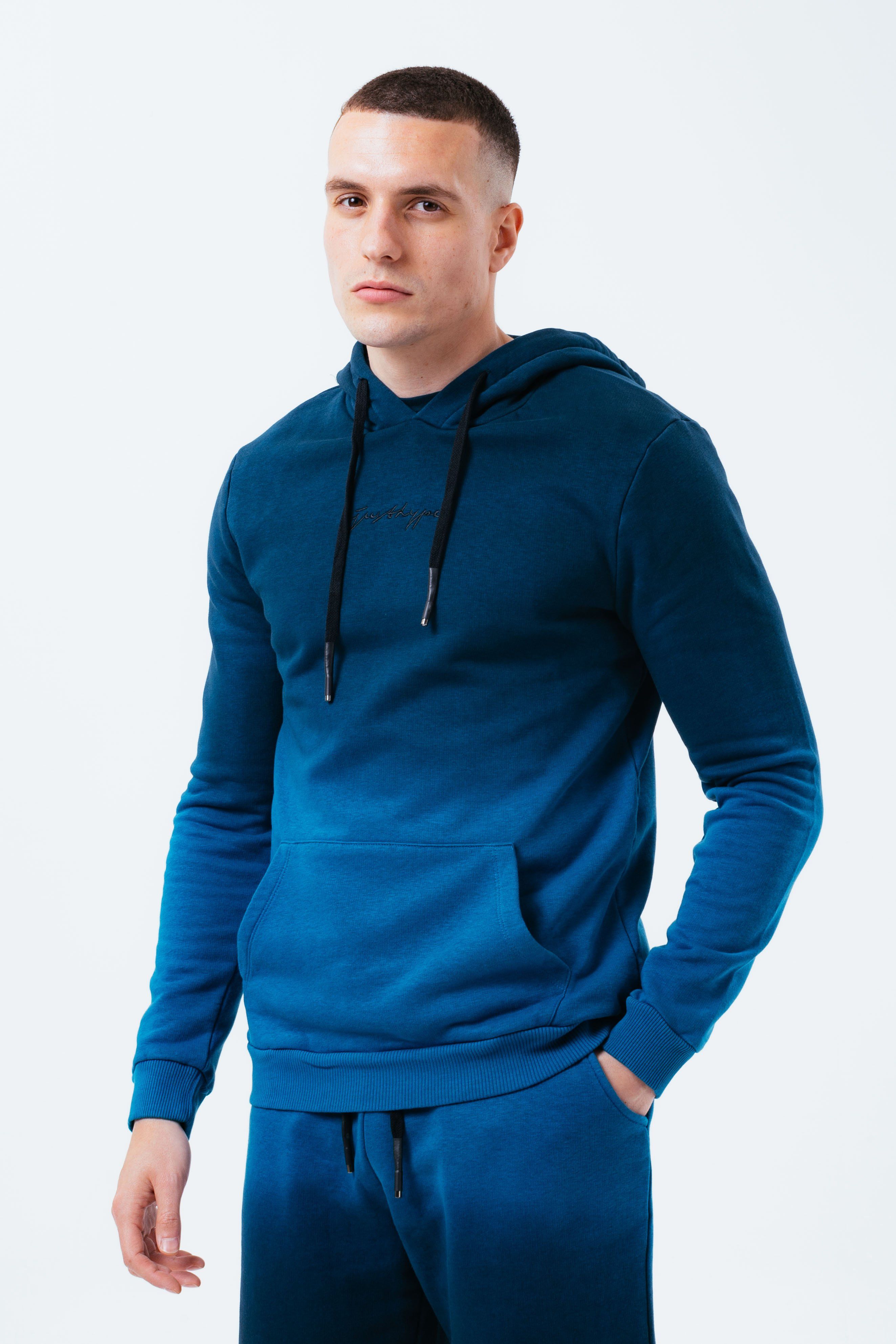 The HYPE. Blue Fade Men's Pullover Hoodie is your new go-to everyday essential. Designed in our standard men's hoodie shape, with a fixed hoot, kangaroo pocket and fitted hem and cuffs. With a 80% cotton and 20% polyester fabric base for supreme comfort and breathable space. With our signature all-over gradient fade effect in a light blue and navy colour palette. Finished with the new! embroidered just hype signature logo embroidered on the front in a contrasting black. Wear with black skinny fit jeans for a smart casual look. Machine washable.