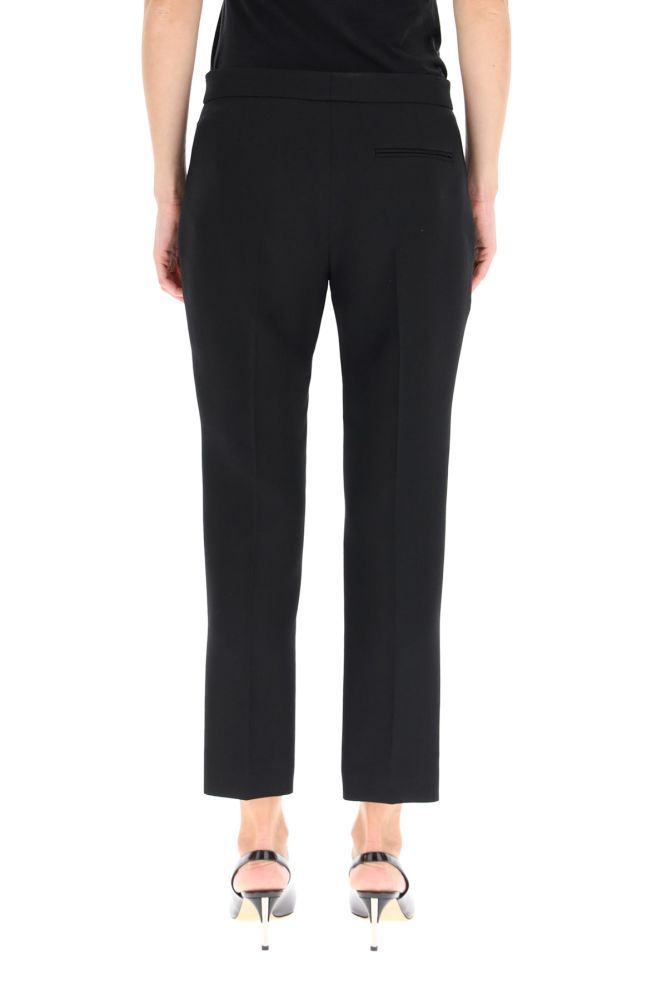 Tailored cigarette trousers by Alexander McQueen in light wool and silk fabric with central pleat and ankle length. The straight and tapered leg line is characterized by side slit pockets, a welt pocket on the back and a front closure with zip and concealed hook. The model is 177 cm tall and wears size IT 40.