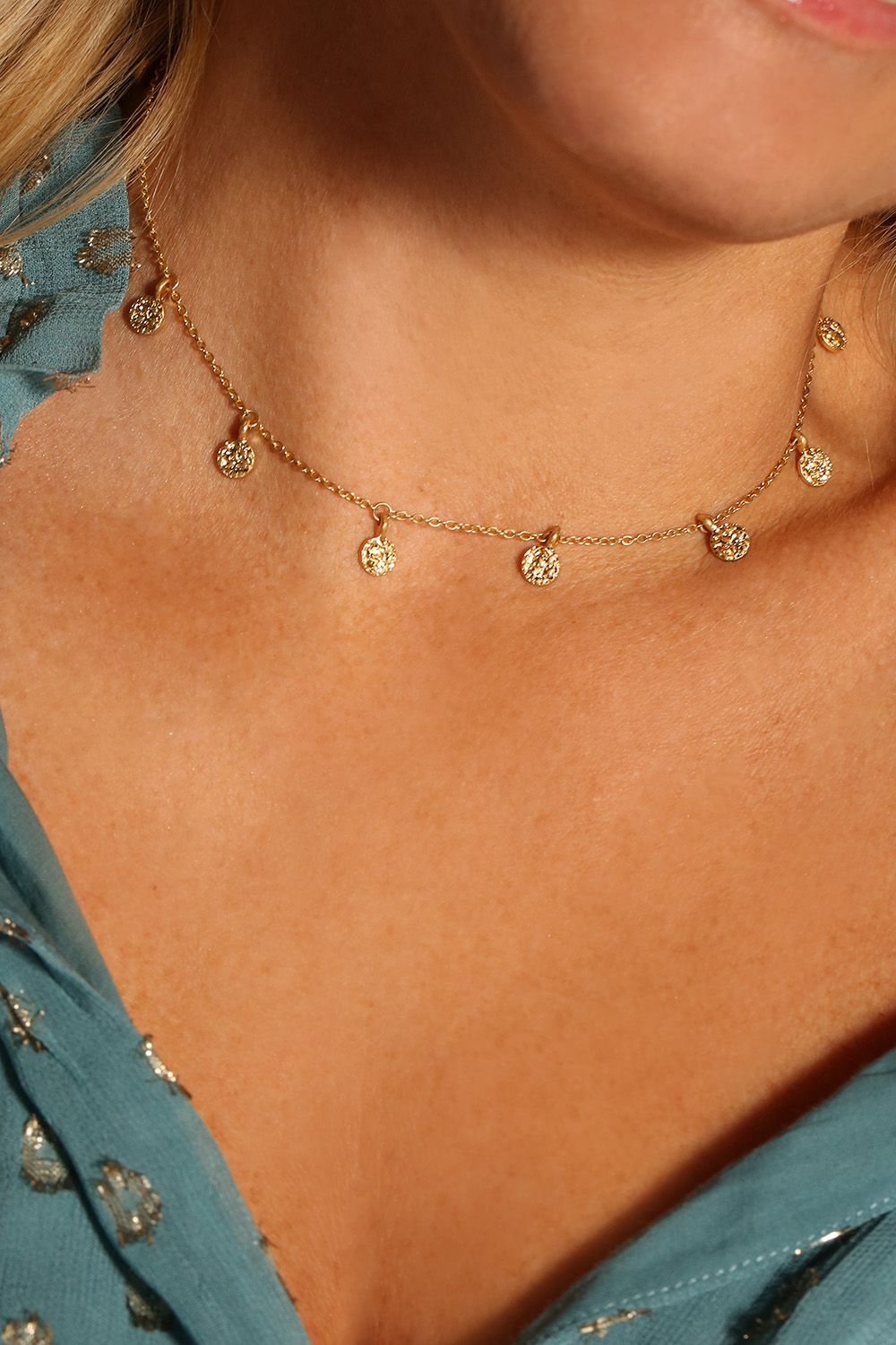 If you love your boho jewellery, this one's for you. It features a dainty gold choker with miniature coins that dance across your neck! The gold plated necklace features hammered gold detailing and looks amazing layered with another longer necklace with a low neckline outfit, or over the top of a jumper during the day! It measures 15 inches and comes with a lobster clasp fastening and 3 inch extender. The Boho choker necklace is designed by Kate Thornton as a classic piece that you can wear with so many looks!