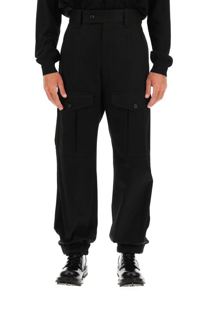 Alexander McQueen trousers made of heavy cotton twill. High-waisted design and oversized fit. Slash pockets, front button closure and hidden zip. Maxi patch pockets on the front with flap and button, back pockets and back pockets. The model is 185 cm tall and wears size IT 46.