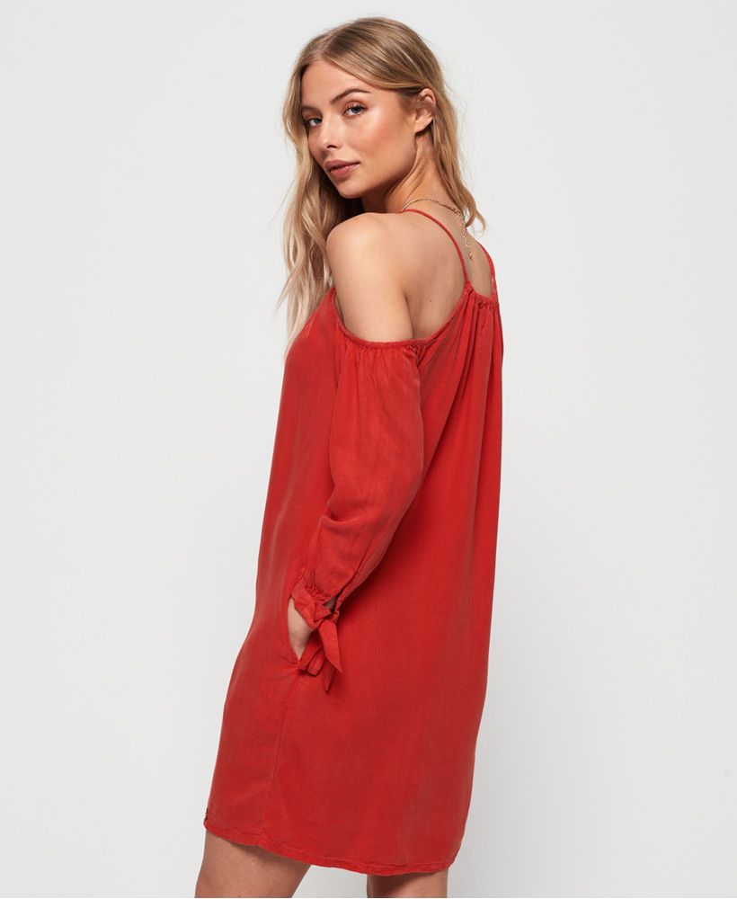 Superdry women's Eden cold shoulder dress. This dress features a cold shoulder design, tie fastening on the cuffs and two pockets in the side seams. Finished with a metal Superdry logo badge above the hem.