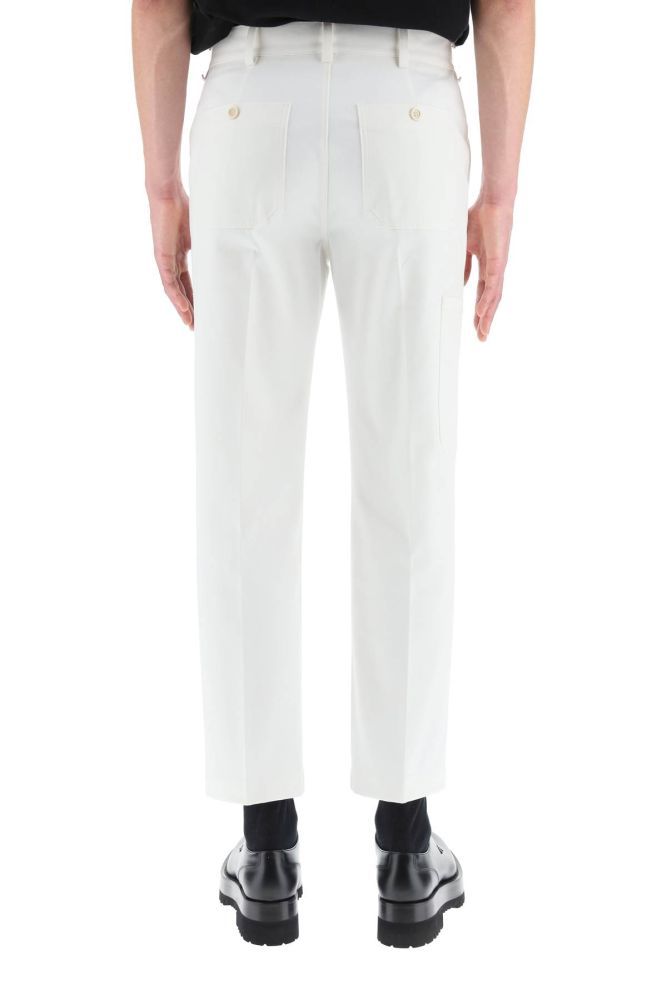 Alexander McQueen informal trousers in white cotton gabardine with McQueen Graffiti logo printed along the leg. Loose straight leg cut, featuring rear patch pockets with horn button, zip fly and button fastening, front slash pockets. Side patch pocket. The model is 185 cm tall and wears a size IT 46.