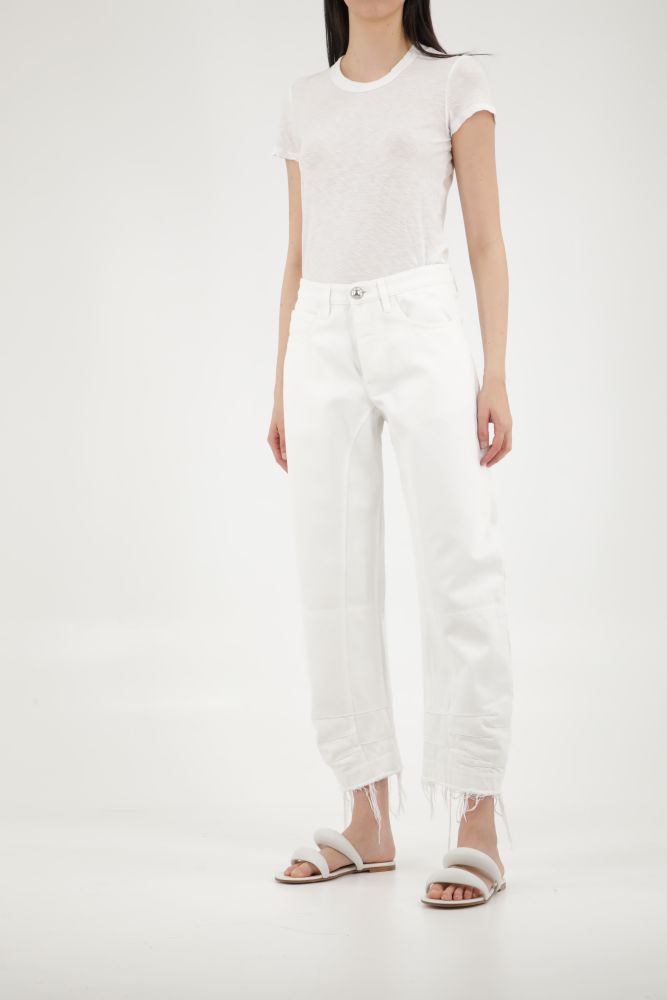 Workwear trousers in white cotton with five pockets design. It features button closure, belt loops and frayed hem on ankles. The model is 180cm tall and wears size 34.