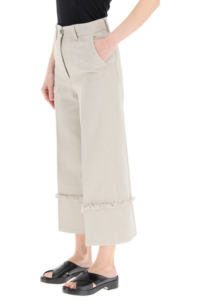 High-waisted culotte trousers in lightweight cotton and linen denim by MSGM. They feature maxi sewn cuffs with fringed trim, zip fly and button closure, side slash pockets, rear patch pockets. Logo label at back. The model is 177 cm tall and wears a size IT 38.