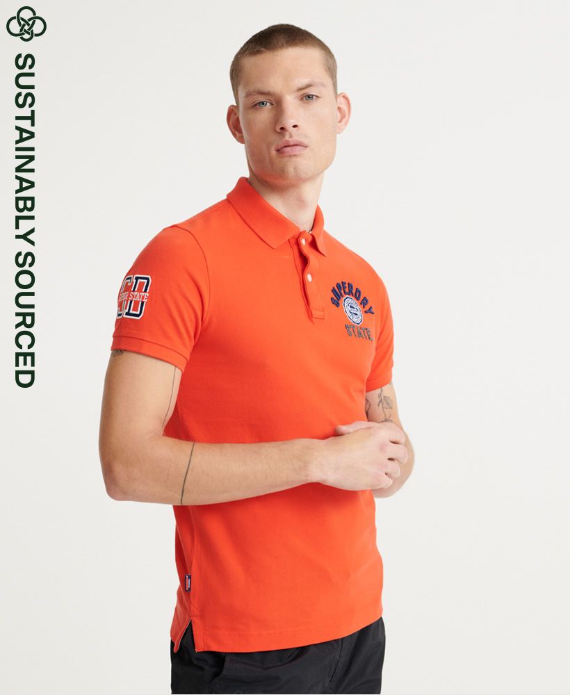 Superdry men's Classic superstate polo shirt. A staple in any wardrobe, this short-sleeved polo features a button fastening at the collar, side splits at the hem and a longer hem at the back. Finished with an embroidered number on one sleeve, and an embroidered Superdry logo on the chest.Slim fit – designed to fit closer to the body for a more tailored lookMade with Organic Cotton - which is grown without the use of artificial chemicals, leading to better soil, 60-90% less water used, and better health for farmers.