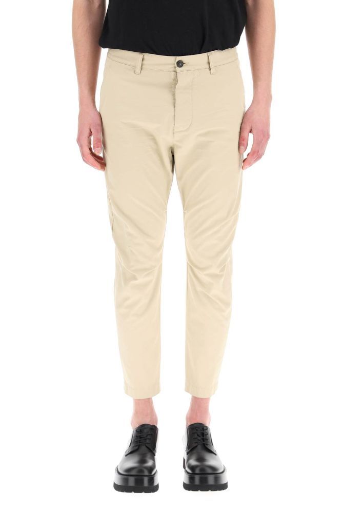 Cotton gabardine pants by Dsquared2, featuring a mid-rise slim fit with long crotch and cropped length. Button fly, side slanted pockets, rear button-through bound pockets, reinforced crotch, ergonomic curvature at the knees. Logo detail printed on the back. The model is 187 cm tall and wears a size IT 48.
