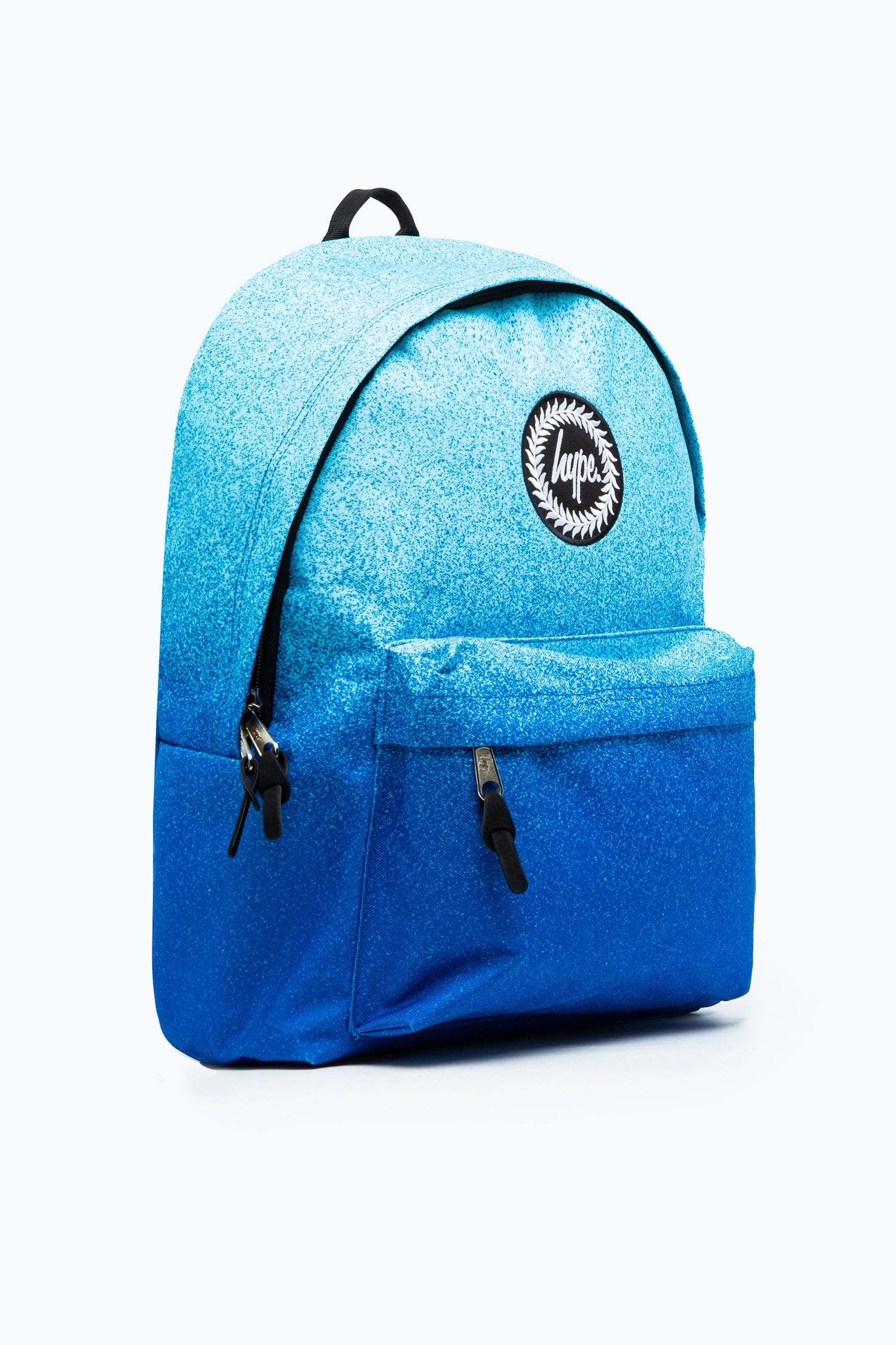 Let us introduce you to the HYPE. Blue Speckle Fade Backpack. Designed in our standard unisex backpack shape and design, measuring at 42cms x 30cms x 12cms, this is the perfect size to transport your matching pencil case, lunch bag and P.E kit. Finished with a front mini pocket, grab handle, embossed zips, branded inside lining and the iconic HYPE. crest badge in monochrome on the front. The straps offer supreme comfort with just the right amount of padding. Wipe clean only.
