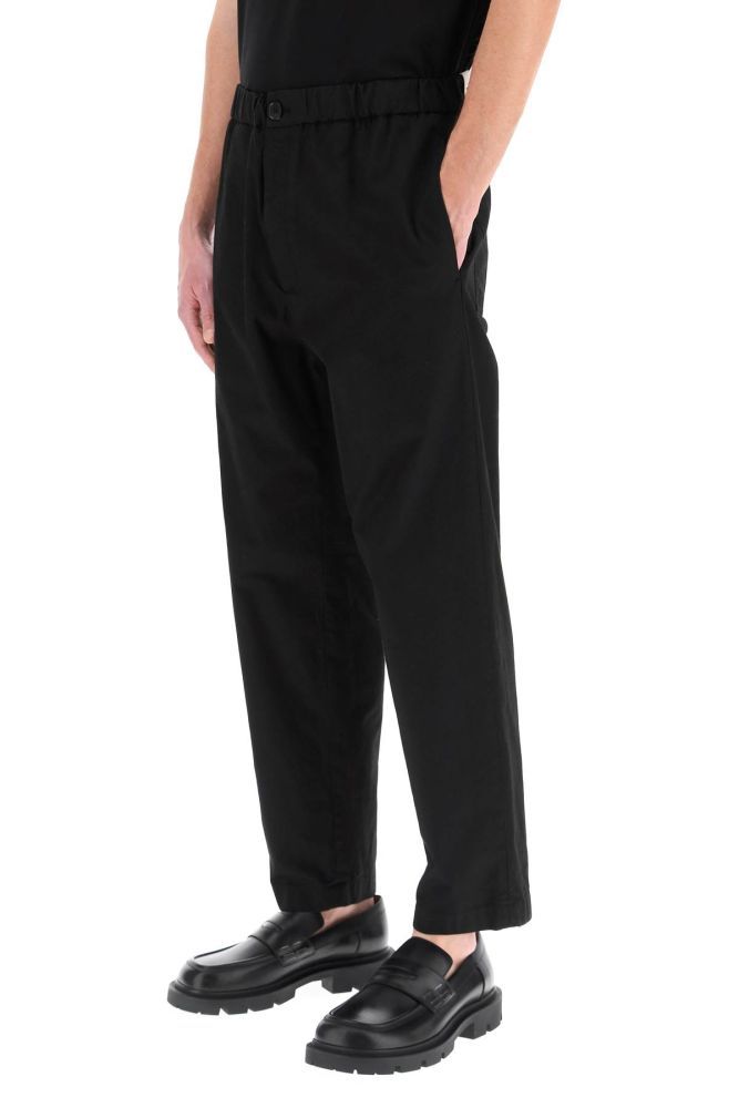 Jil Sander+ casual trousers in lightweight cotton featuring a relaxed fit and a tapered leg cut with elasticated waistband. Closure with horn button and zip fly, side seam pockets, rear patch pockets. Logo loop on the back waist. The model is 187 cm tall and wears a size IT 46.