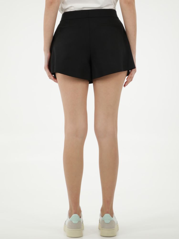 Black shorts characterized by a waist belt with an adjustable red logoed buckle. It features front pleats, two side welt pockets and two rear welt pockets. The model is 178cm tall and wears size 28.