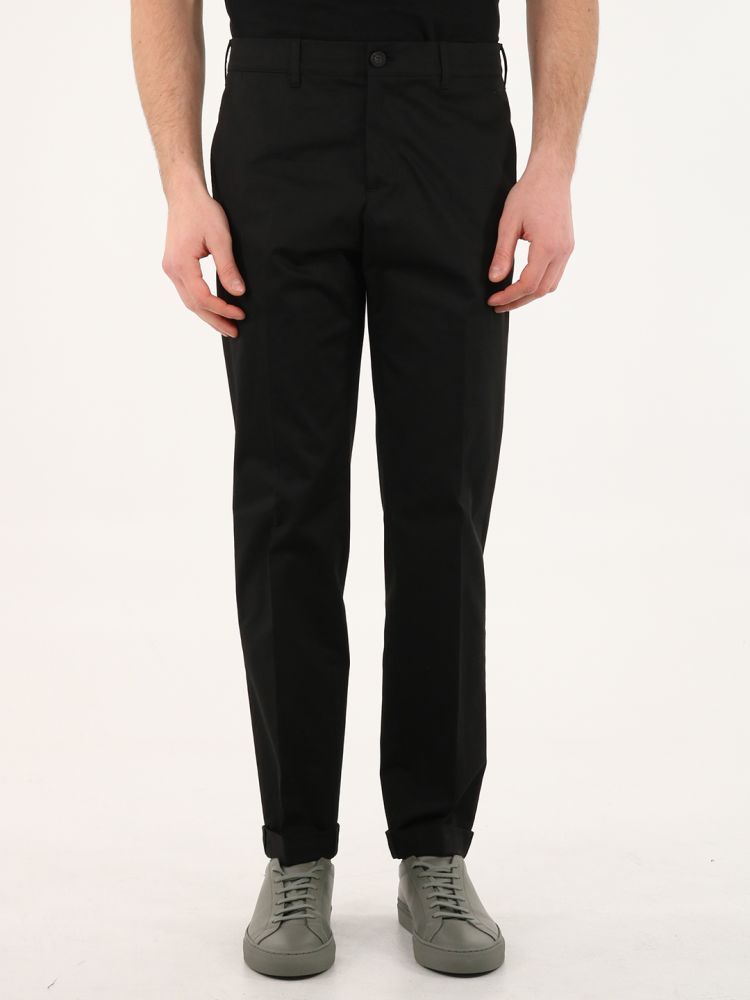 Golden collection black chinos with straight leg and two front pockets. It features a detachable white patch with embroidered red letter G and two double gold stars on the back. The model is 184cm tall and wears size 48.