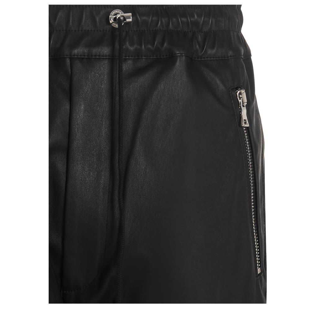 Leather pants with an elastic waistband and a drawstring at the waist, a low crotch, turn-ups on leg bottoms and silver hardware.