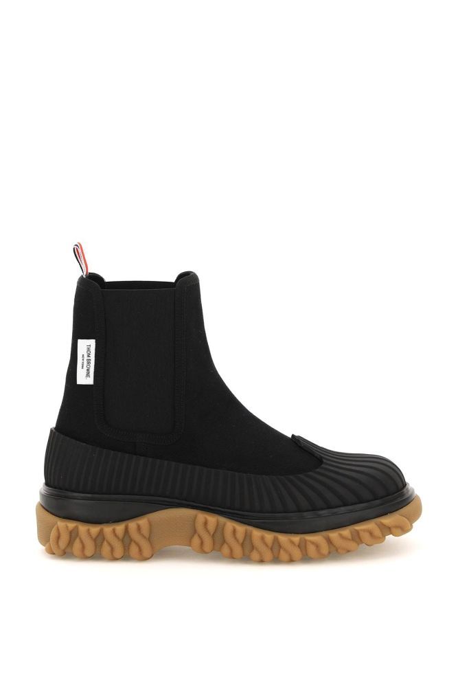 Duck chelsea boots by Thom Browne crafted in water repellant canvas with ridged rubber-coated base and toe. Side elasticated inserts and rear loop tab in the iconic three-tone striped ribbon. Fabric interior with removable insole, double-layer rubber sole with embossed chain motif on the bottom. 