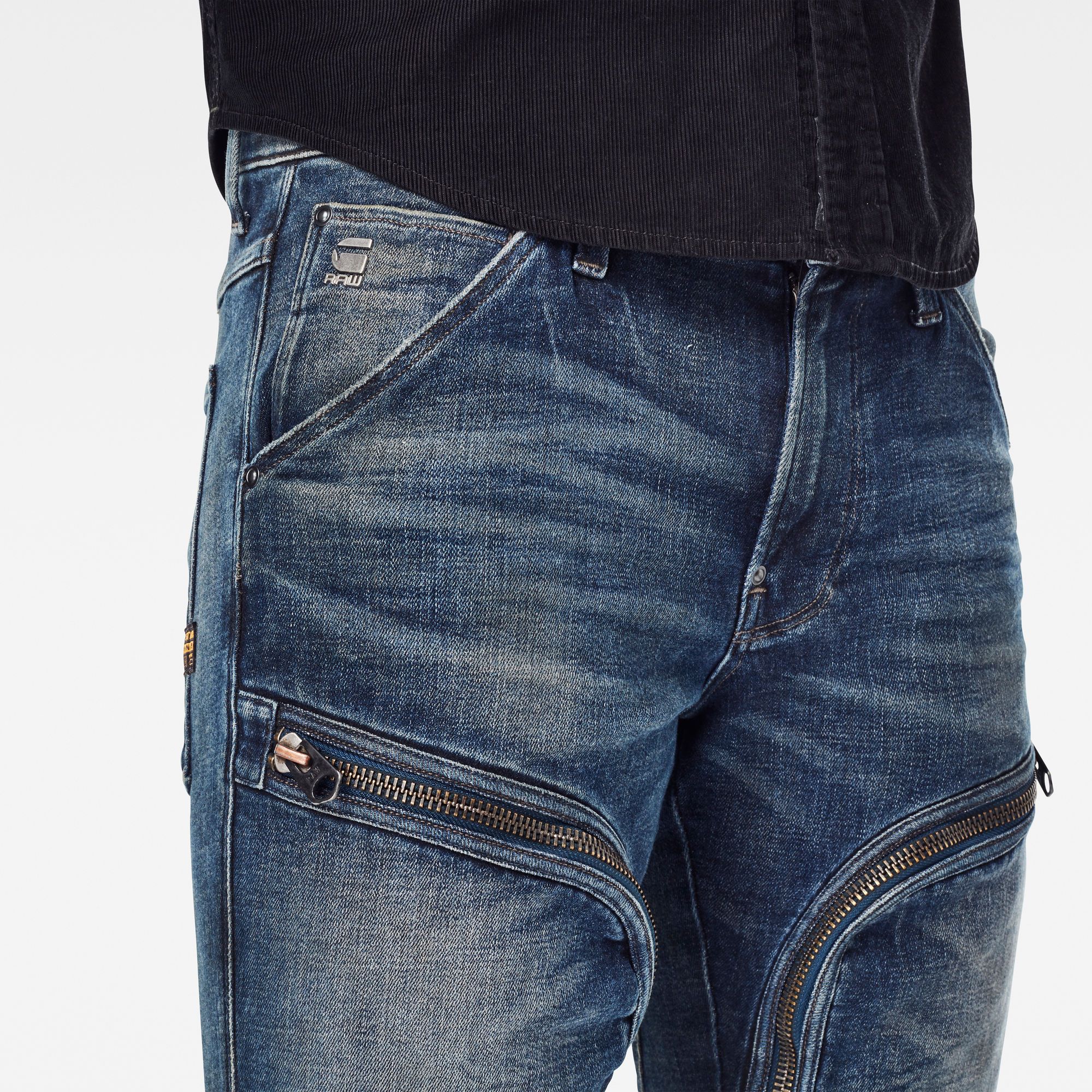 Fitted waistband. Mid waist. Rough zippers set at upper leg pockets. Engineered knee panels. 5-pocket construction and thigh pockets. Zip fly. Zip & button closure. Versatile, high quality  superstretch quality with an authentic denim aesthetic, superb recovery, soft handfeel and pure indigo cast. This shade is made with sustainable aniline-free pre reduced indigo technology. Rough zip pockets at upper leg distinguish the Air Defence zip skinny jeans. Inspired by fighter pilot suits that feature map pockets allowing the pilot to access them while seated during the flight. These pants are cut in a skinny silhouette with 3D legs, created by the inner leg paneling and knee seams. Additional inset pockets and patched on back pockets complete this style. Weight 12.3 oz denim