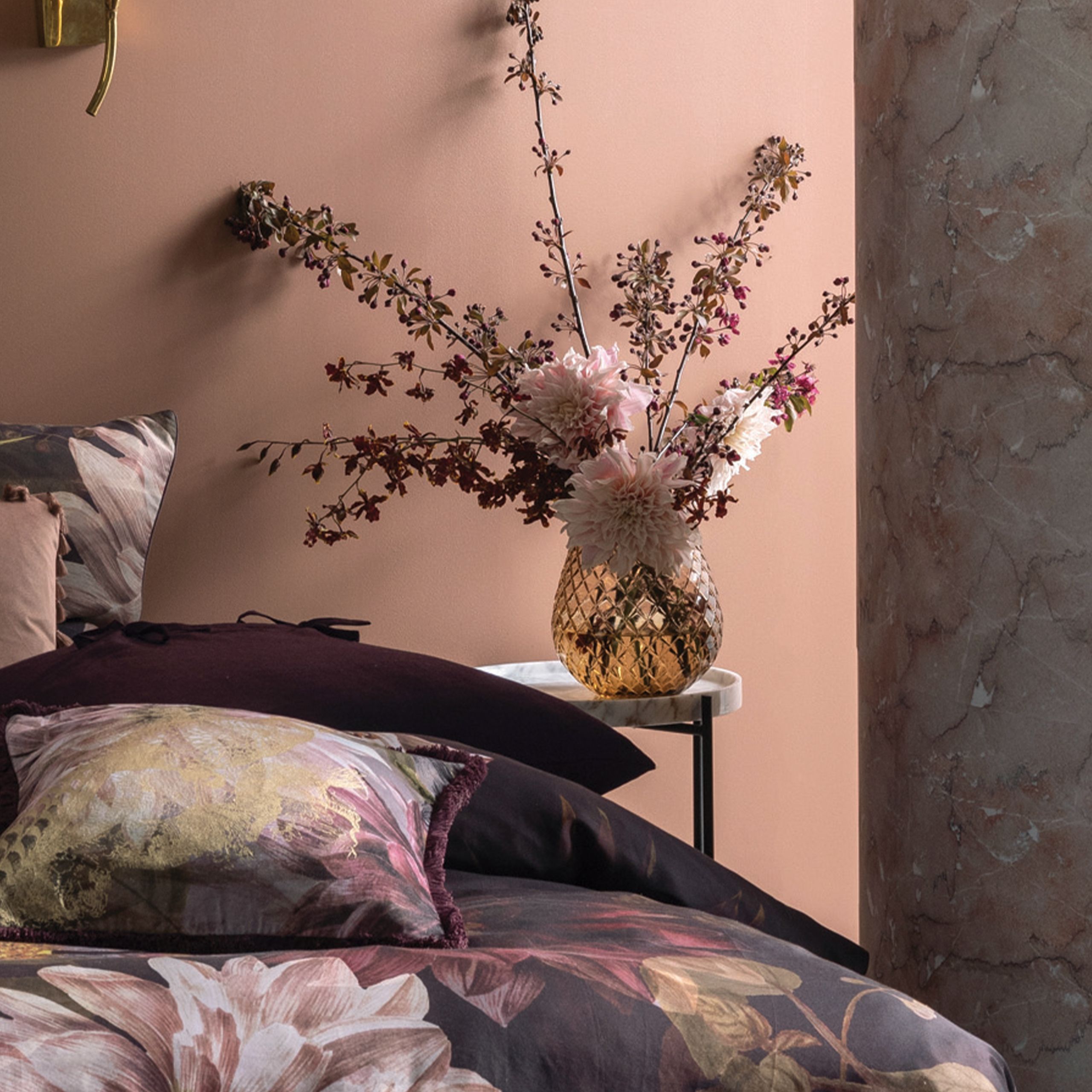 Dark and serene, a stunning floral, embodying a style that has become a signature look from our studio. This Dutch Masters inspired print features an array of foliage and tropical flora in the most delicious and richly saturated shades of plum and wine. Printed on a cotton sateen, this luxurious story is brought to life with tactile printed velvet and gold accented accessories.