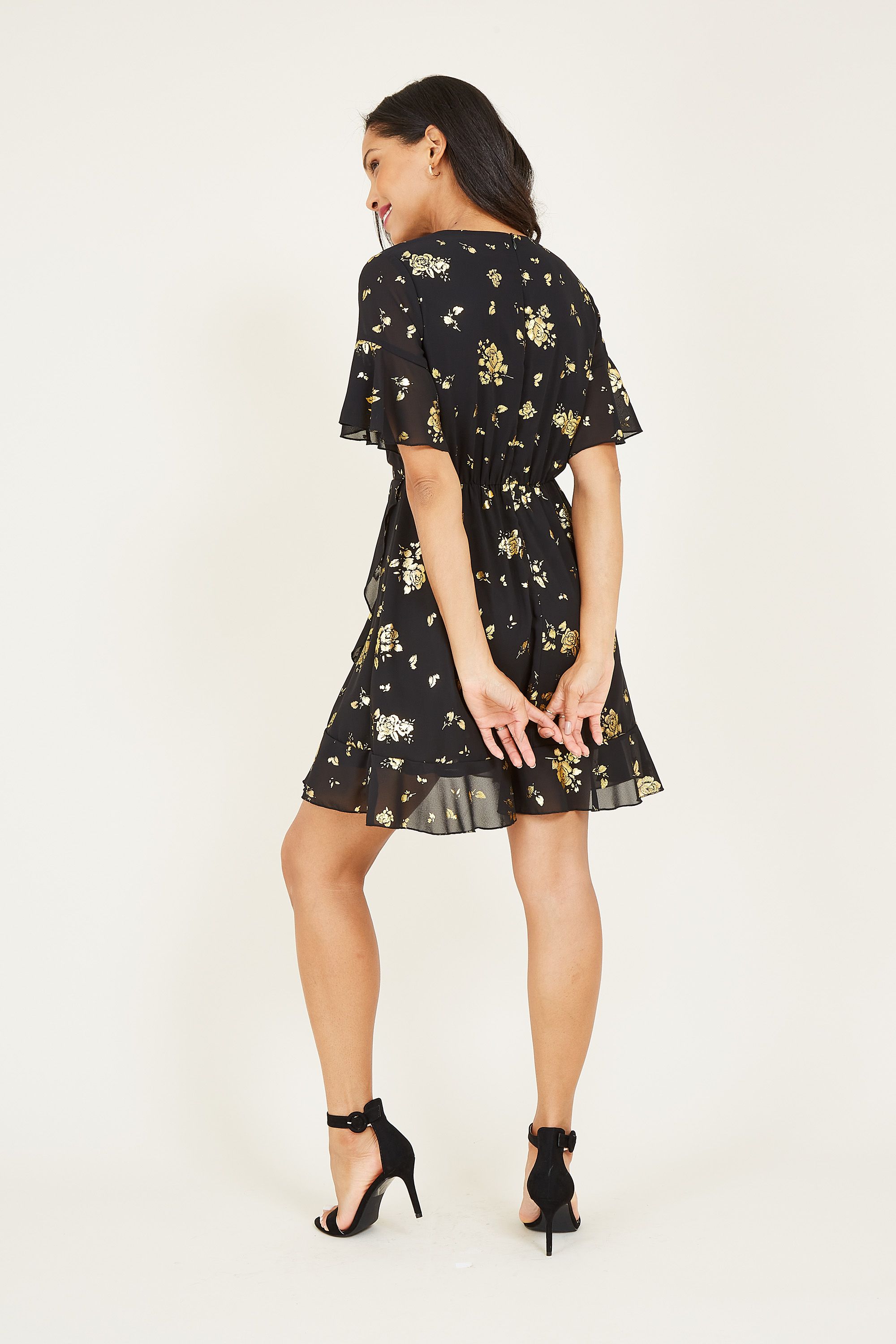Printed with pretty foil florals running from the shoulder to the hemline, this Mela Foil Floral Skater Dress is a wardrobe hit. Featuring lightweight fabric that ties at the waist, it's styled with short floaty sleeves and gentle ruffles. A lining runs undernetah to aid movement, accessorize with anything from trainers to heels.
