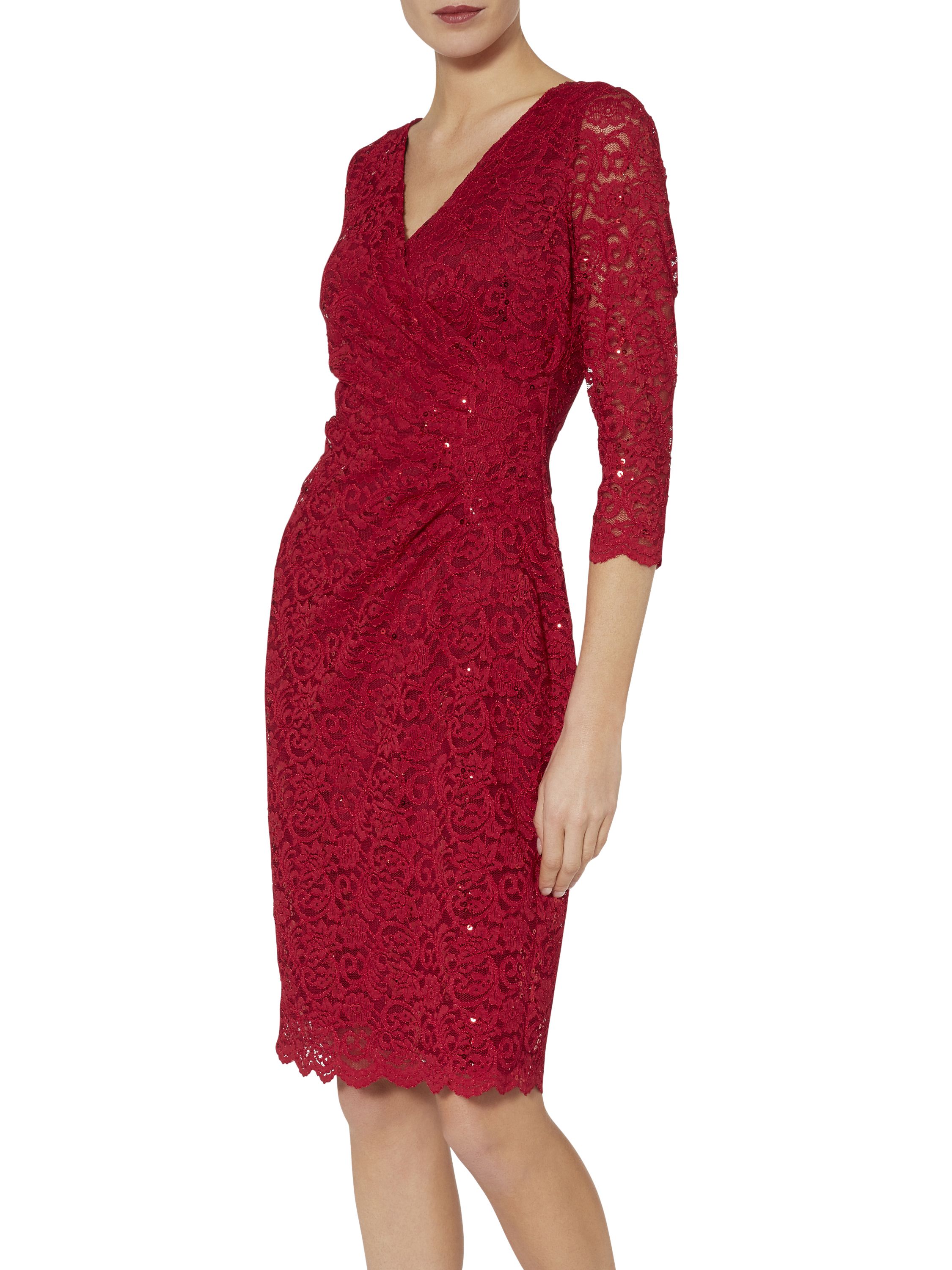 Look dazzling in this beautiful dress by Gina Bacconi. Crafted in a stretch sequin lace it features a wrap top bodice with a gathered side to create a flattering silhouette and a v shaped neckline front and back. This dress is lined with sheer sleeves with a scalloped hem and sleeve detail.