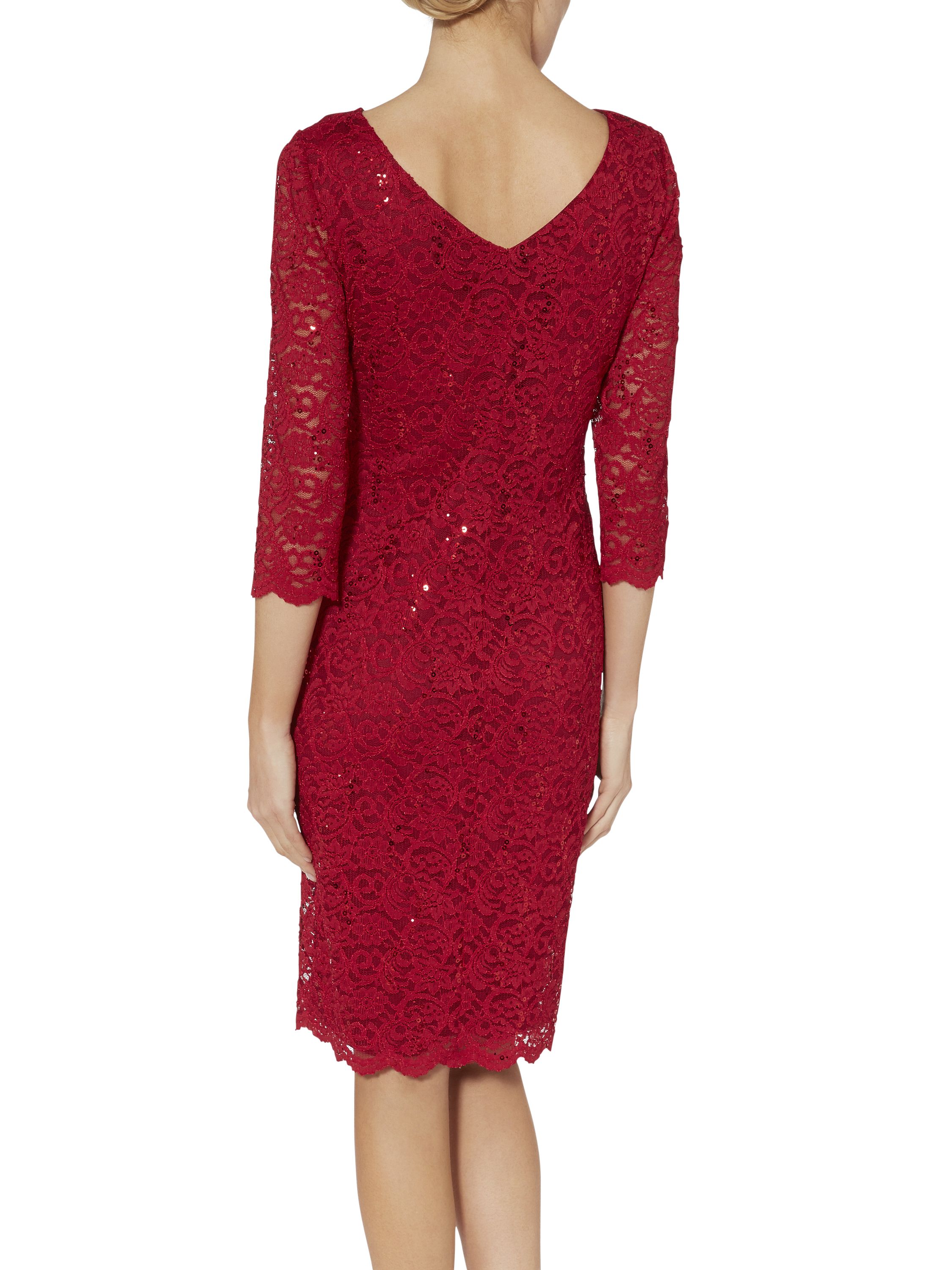Look dazzling in this beautiful dress by Gina Bacconi. Crafted in a stretch sequin lace it features a wrap top bodice with a gathered side to create a flattering silhouette and a v shaped neckline front and back. This dress is lined with sheer sleeves with a scalloped hem and sleeve detail.