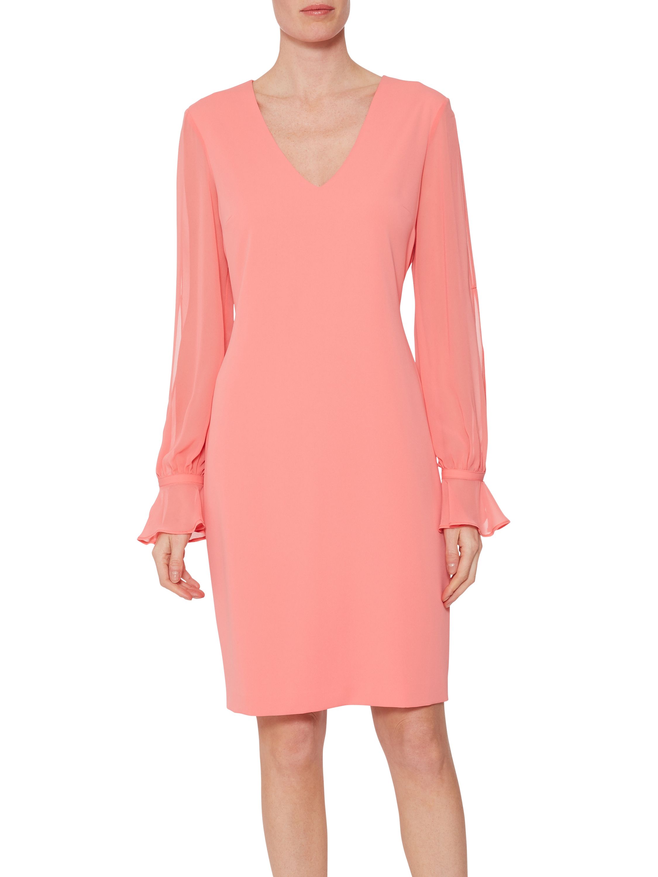 This crepe and chiffon dress by Gina Bacconi is a must-have piece this season. The dress takes a simple shift dress made out of crepe and features a stunning sheer chiffon sleeve which is finished with a dainty frill and is cuffed. With a V shaped neckline. The dress is fully lined and fastens with a concealed back zip.