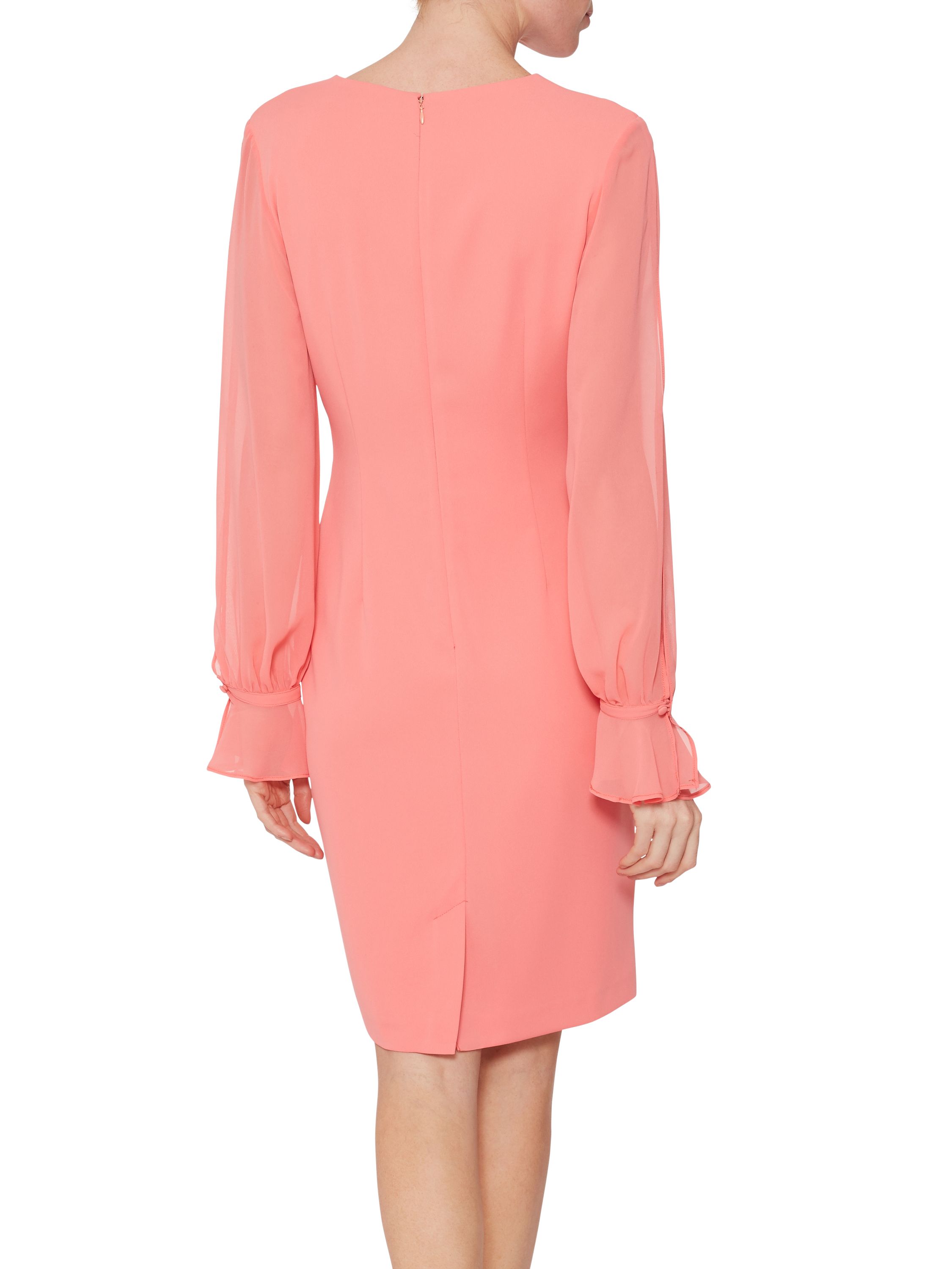 This crepe and chiffon dress by Gina Bacconi is a must-have piece this season. The dress takes a simple shift dress made out of crepe and features a stunning sheer chiffon sleeve which is finished with a dainty frill and is cuffed. With a V shaped neckline. The dress is fully lined and fastens with a concealed back zip.
