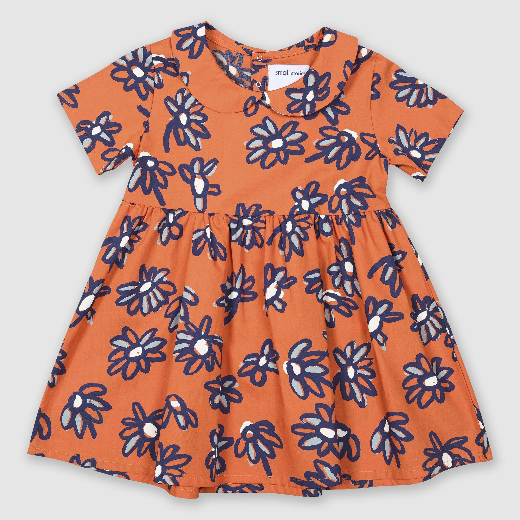 Lightweight 100% cotton dress with our bespoke painted daisy print in orange with blues and white. Features a Peter Pan Collar and press stud back opening for ease of dressing.