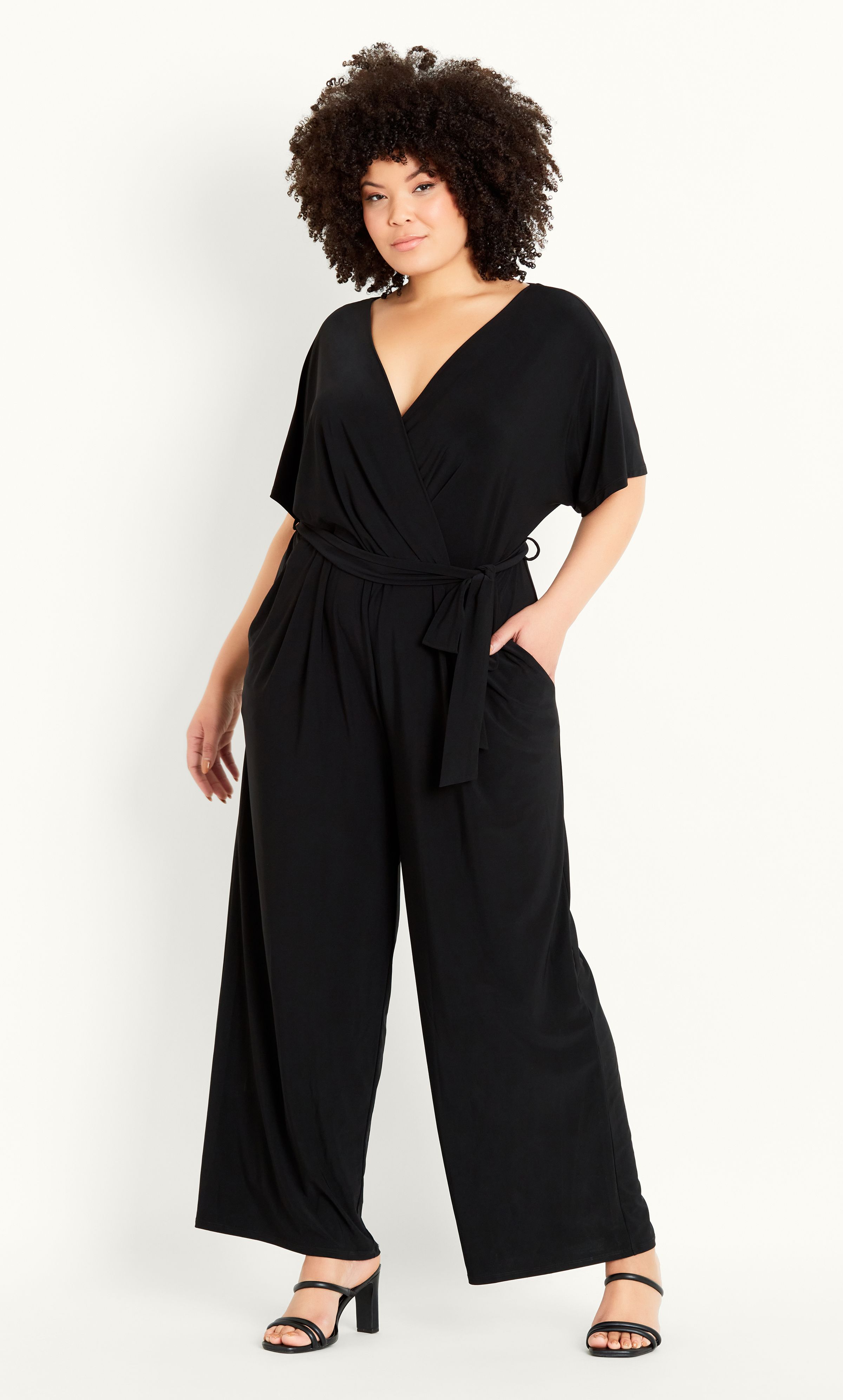 Sleek, chic and all kinds of curve-loving, the Wrap Tie Belt Jumpsuit is as flattering as it is utterly on-trend! Flirting with a plunging V-neck line and cinched waist, as well as a fashionable wide leg, this jumpsuit is a go-to when it comes to classy cocktails and after work drinks. Key Features Include: - Faux wrap V-neckline - Short sleeves - Side pockets - Elasticated waistline - Removable self-tie waist belt - Soft stretch fabrication - Relaxed leg - Unlined - Pull up style - Full length Add a touch of opulence with statement earrings, strappy stilettos and a fierce red lip.