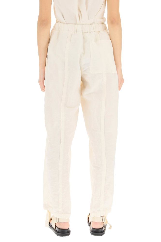 Loose fit trousers in linen and cotton fabric by Jil Sander, detailed with drawstring waist and cuffs. Button fly, centre leg seams, side inseam pockets, a patch pocket on the back. The model is 177 cm tall and wears a size DE 34.