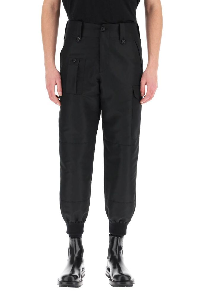 Alexander McQueen military style sports trousers cut from sustainable polyfaille to a straight leg loose fit, detailed with patch pockets with horn buttons on the back. Zip fly and button closure, front welt pockets, one front pocket and a cargo side pocket. Finished with ribbed knit cuffs. The model is 185 cm tall and wears a size IT 46.