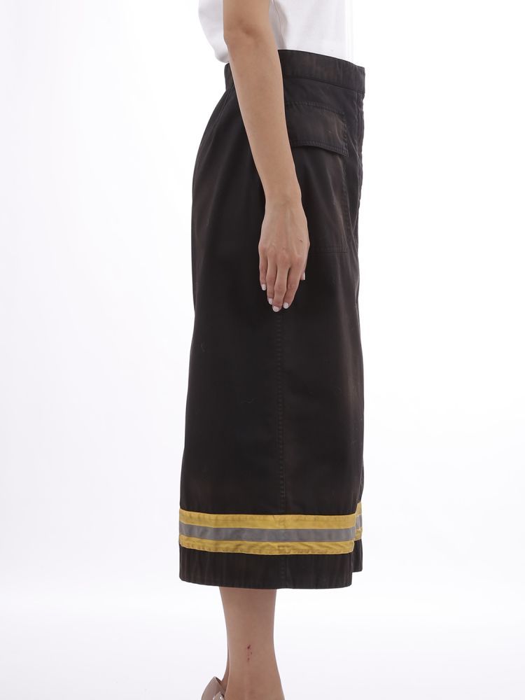 Black longuette skirt with flap pockets and concealed fastening on the front. From the clear reference to the uniforms of firemen, this skirt has a yellow band with a reflective band on the bottom.The model is 1,77 tall and wears size S / 40IT / 26US / 36FR / 8UK