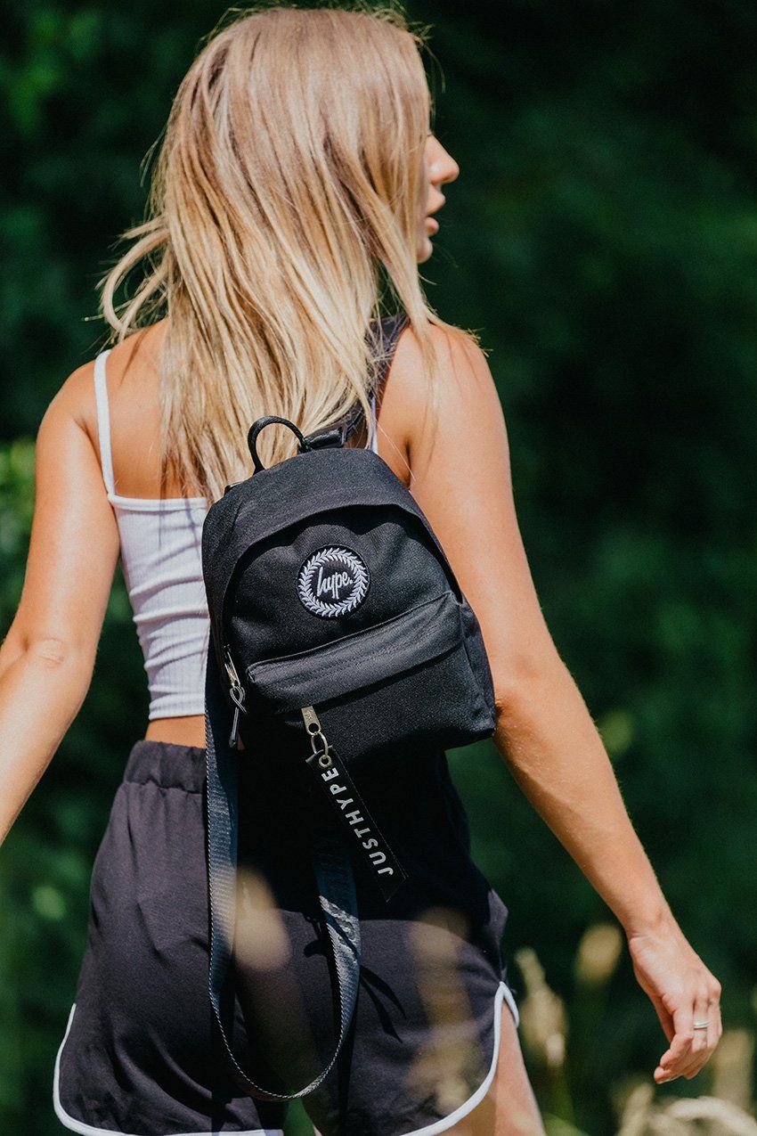 We see you checkin' out the HYPE. black mini backpack. An all over black fabric base, finished with a monochrome embossed puller tag and the iconic HYPE. crest badge. This is a mini version of our standard backpack shape. Perfect for storing your essential items while you're on the go. Wipe clean only.