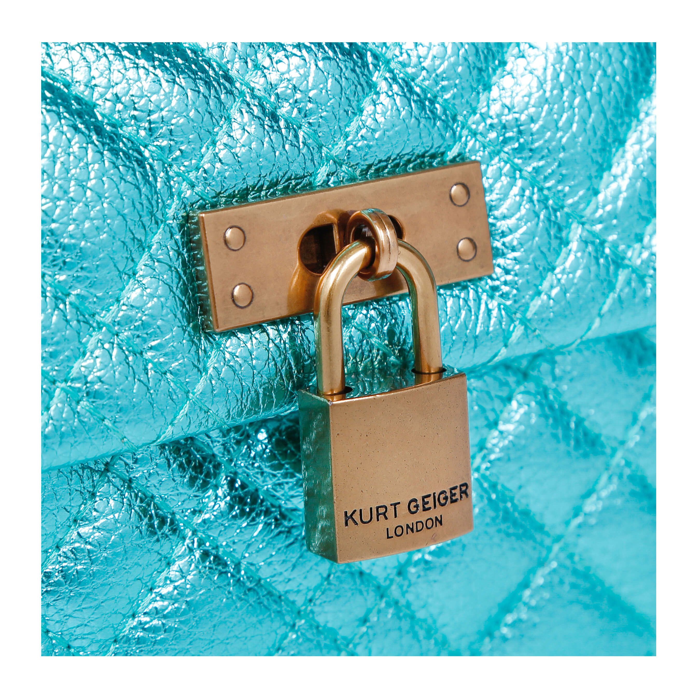 The mini metallic blue KGL Brixton Lock Bag is crafted from fabric with overstitch quilting design. There is an antiqued brass branded padlock on the front flap.
